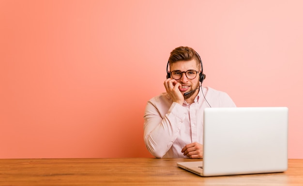 Young man working in a call center biting fingernails, nervous and very anxious.