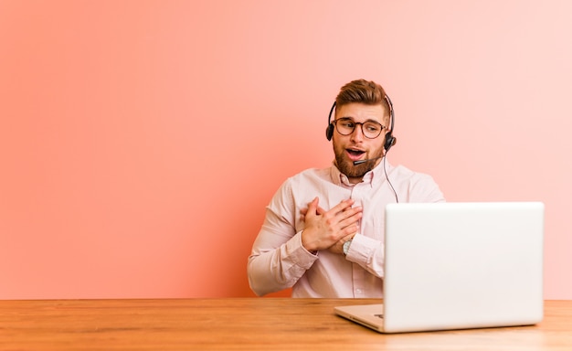 Young man working in a call center has friendly expression, pressing palm to chest. Love concept.