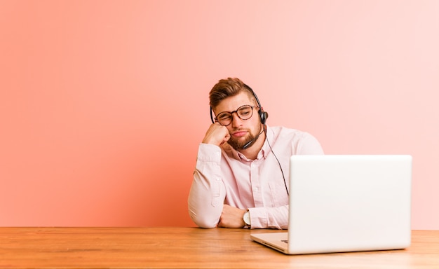 Young man working in a call center who feels sad and pensive, looking at copy space.