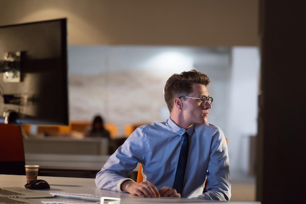 Young man working on computer at night in dark office. The designer works in the later time.