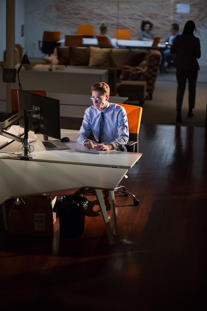 Young man working on computer at night in dark office. The designer works in the later time.