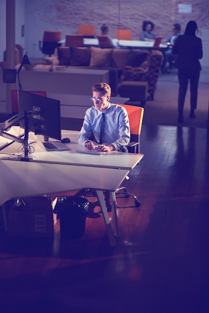 Young man working on computer at night in dark office. the\
designer works in the later time.