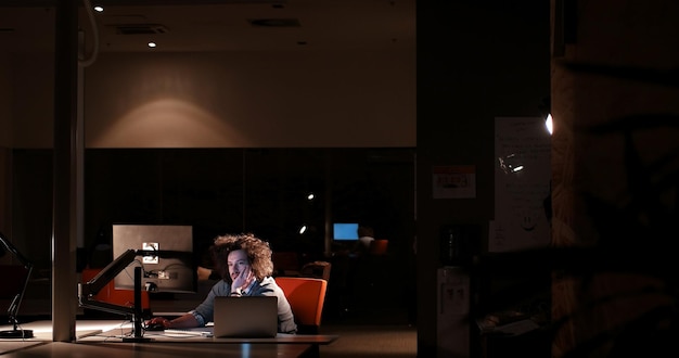 Young man working on computer at night in dark office. The designer works in the later time.