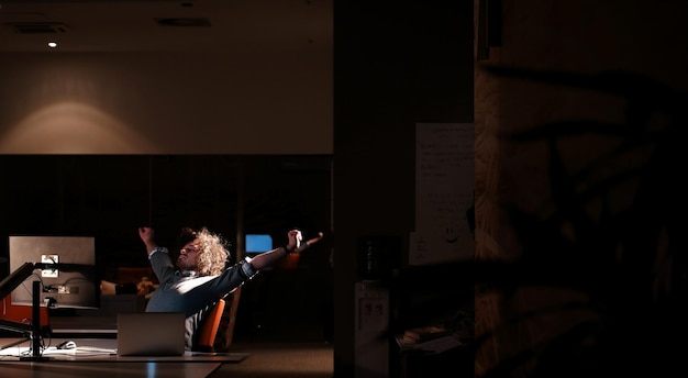 Young man working on computer at night in dark office. the\
designer works in the later time.