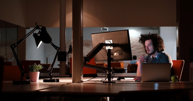 Young man working on computer at night in dark office. the\
designer works in the later time.