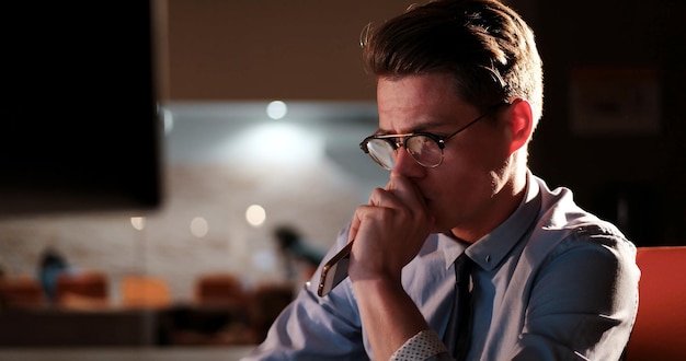 Young man working on computer at night in dark office. the\
designer works in the later time.