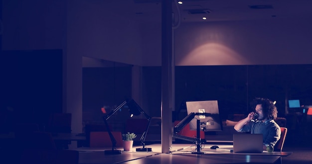 Young man working on computer at night in dark office. the
designer works in the later time.