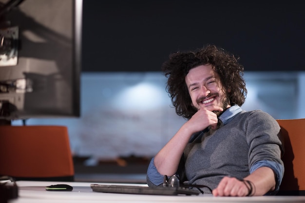 Young man working on computer at night in dark startup office.\
the designer works in the later time.