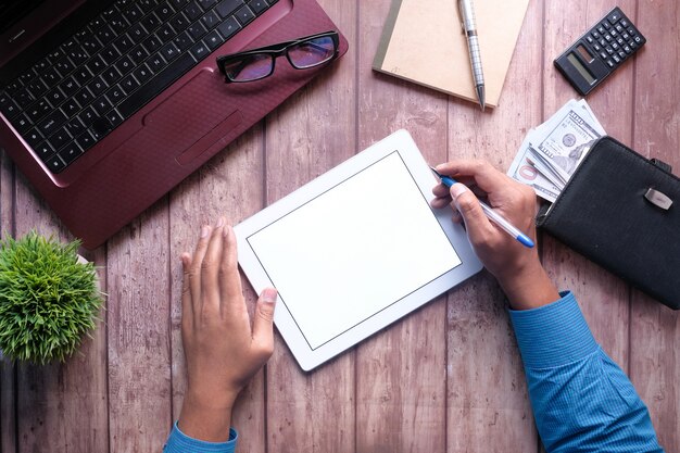 Young man working on digital tablet with laptop and notepad on table