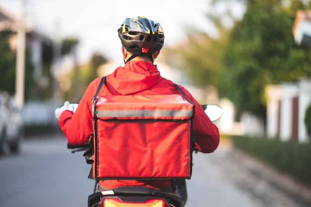 Young man working for a food delivery service checking with road motorcycle in the city