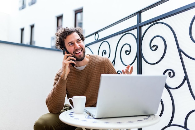 Young man working from home using smart phone and notebook\
computer.portrait of businessman talking on mobile phone and\
drinking coffee in the morning