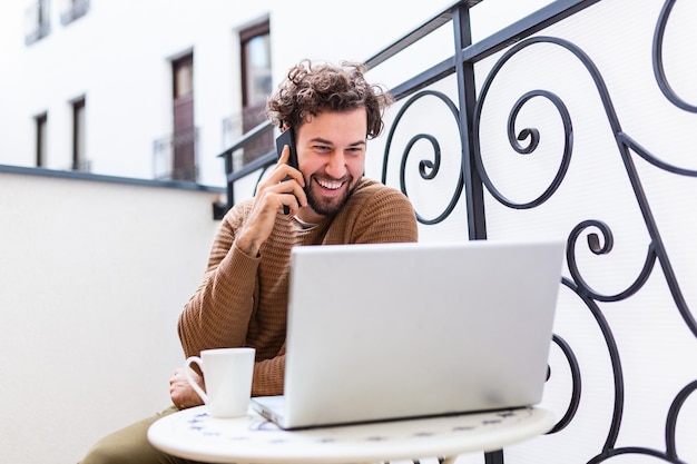 Young man working from home using smart phone and notebook\
computer.portrait of businessman talking on mobile phone and\
drinking coffee in the morning