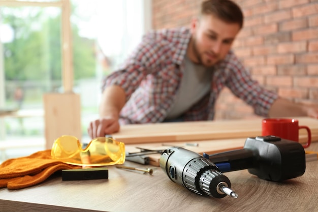 Young man working indoors focus on electric screwdriver