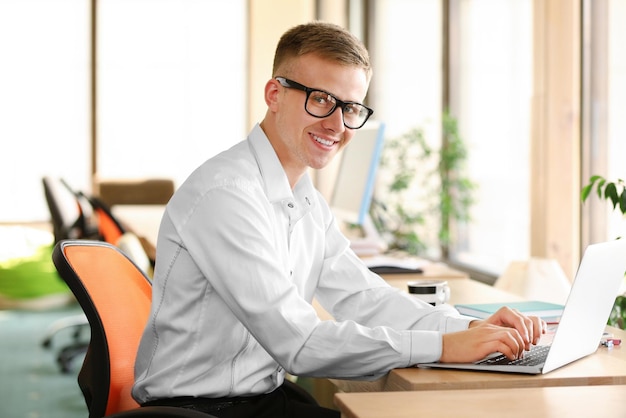 Photo young man working on laptop in office