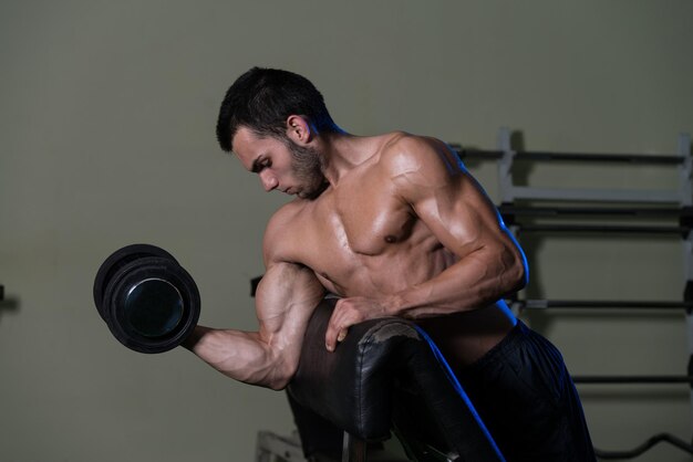 Young Man Working Out Biceps  Dumbbell Concentration Curls