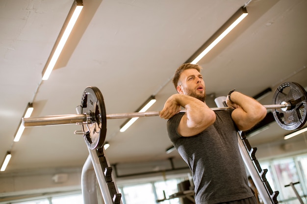 Young man working out with barbells in the gym