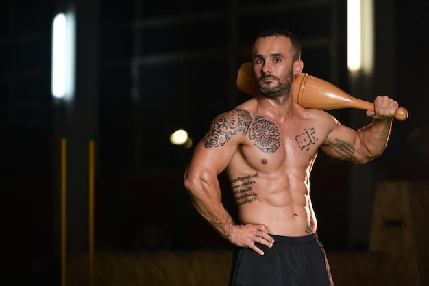 Young Man Working Out With Bowling Pin In A Gym  Bodybuilder Doing Heavy Weight Exercise In Fitness Centar