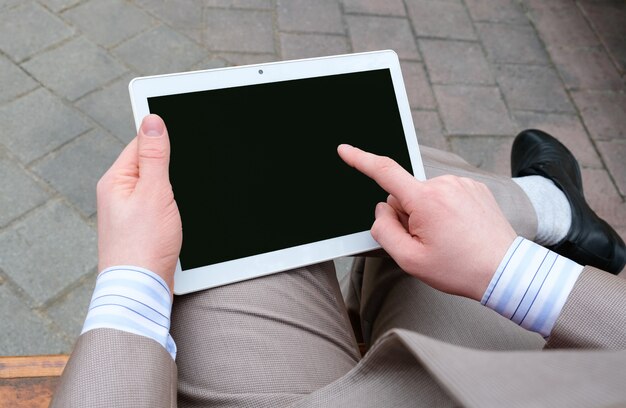 Young man working on a tablet on the bench