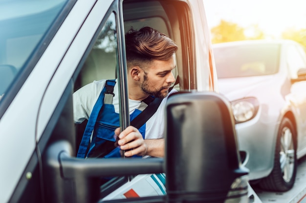 道路でけん引サービスで働いている若い男。道端での援助の概念。