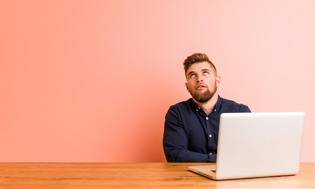 Young man working with his laptop tired of a repetitive task