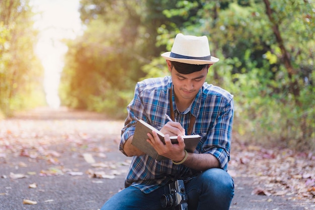 young man writing in diary on road