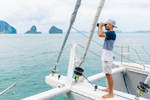 Young man yacht looking through binoculars. travel and active life.