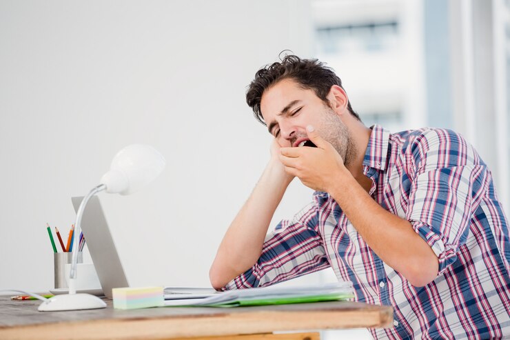 Photo young man yawning at his desk