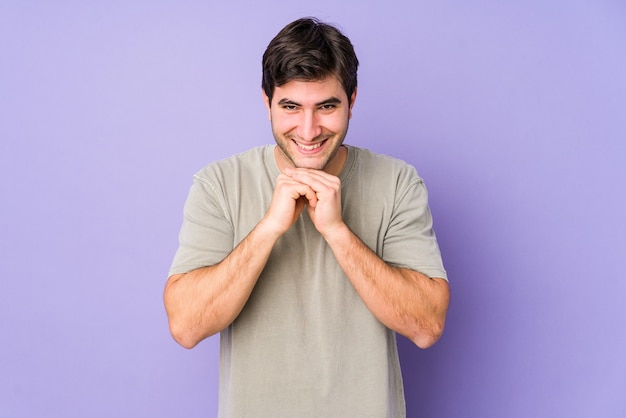 Young man on yellow keeps hands under chin, is looking happily aside.