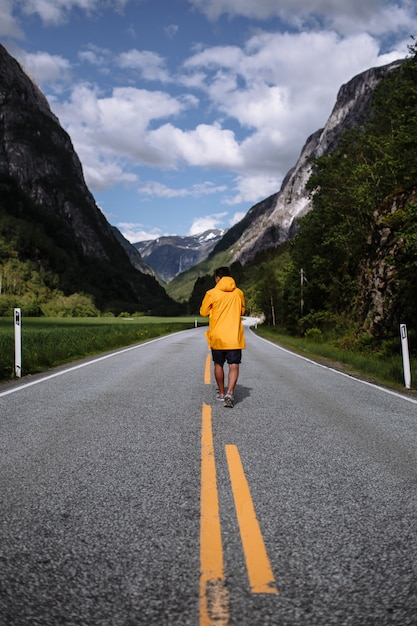 Young man in a yellow raincoat on the road