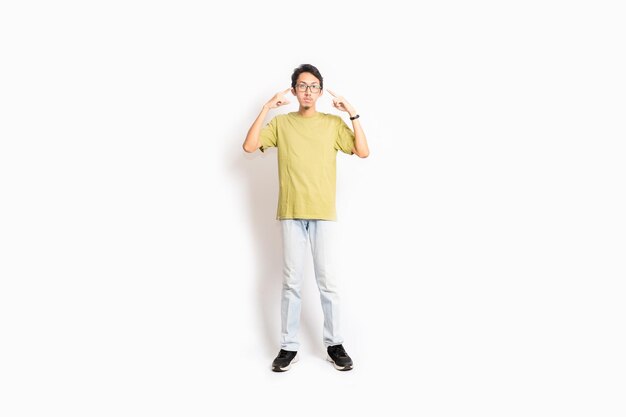 A young man in a yellow t - shirt is posing with his hands up.