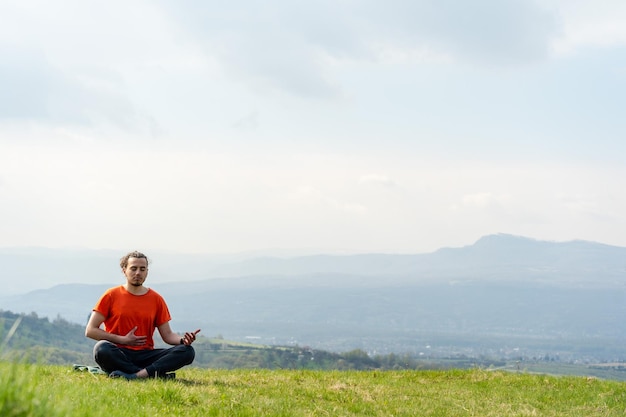 Young man do yoga on the mountain peak