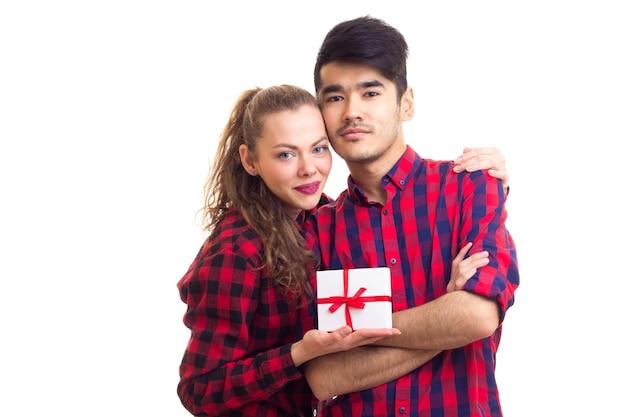 Young man and young happy woman with white little present wearing in red plaid shirts hugging