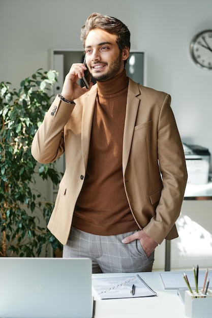 Young manager in glasses using smartphone