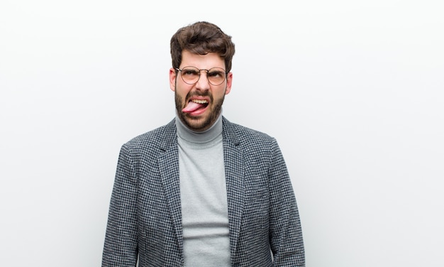 Photo young manager man feeling disgusted and irritated, sticking tongue out, disliking something nasty and yucky against white wall