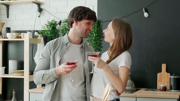 Young married couple drinks cocktails in the kitchen at home