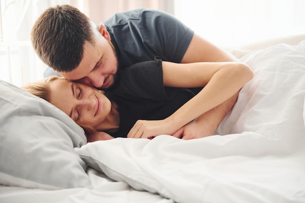 Young married couple have leisure together in bedroom at daytime.