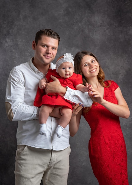 A young married couple is holding a little daughter in their arms the child is looking at the camer