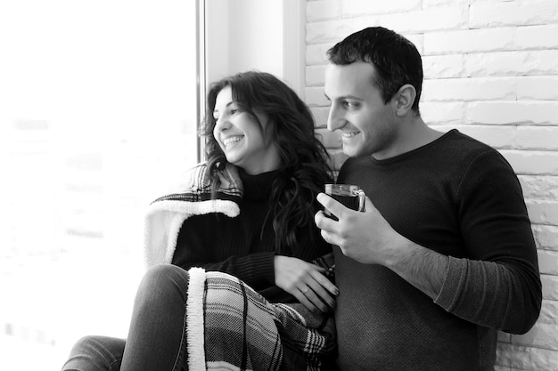 A young married couple looks out the window of a new apartment