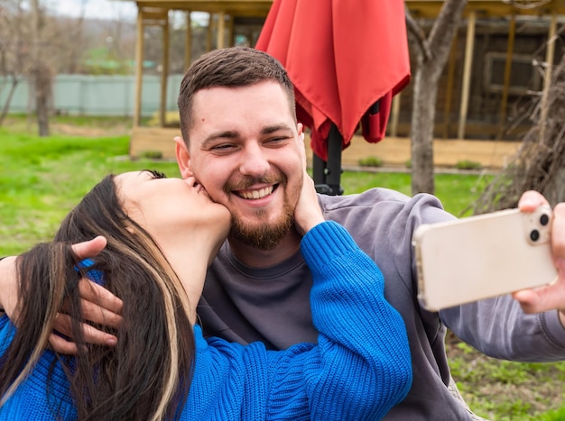 Photo young married couple making a selfie and laughing on the backyard of their house