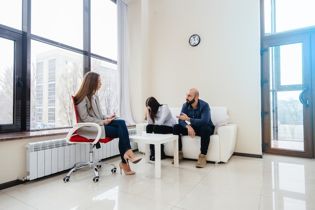 A young married couple of men and women talk to a psychologist\
at a therapy session. psychology.