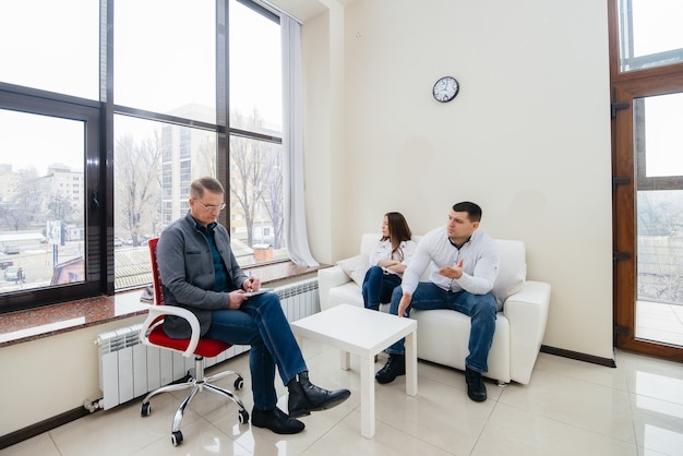 A young married couple of men and women talk to a psychologist\
at a therapy session. psychology.