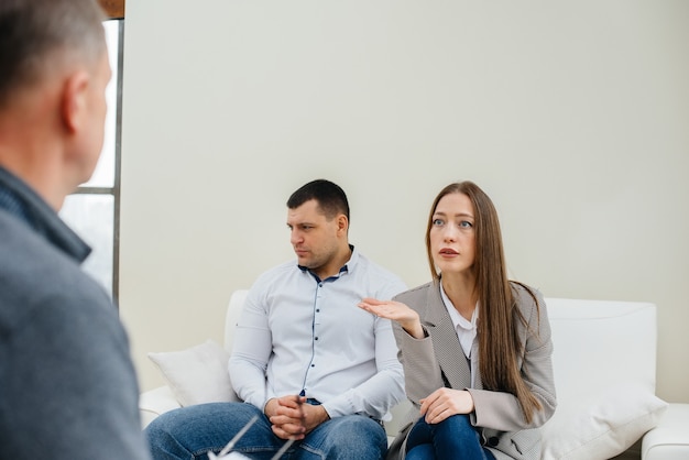 A young married couple of men and women talk to a psychologist\
at a therapy session. psychology.