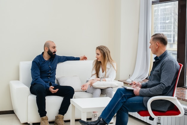 A young married couple of men and women talk to a psychologist\
at a therapy session. psychology.