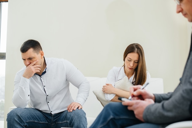 A young married couple of men and women talk to a psychologist at a therapy session. Psychology.