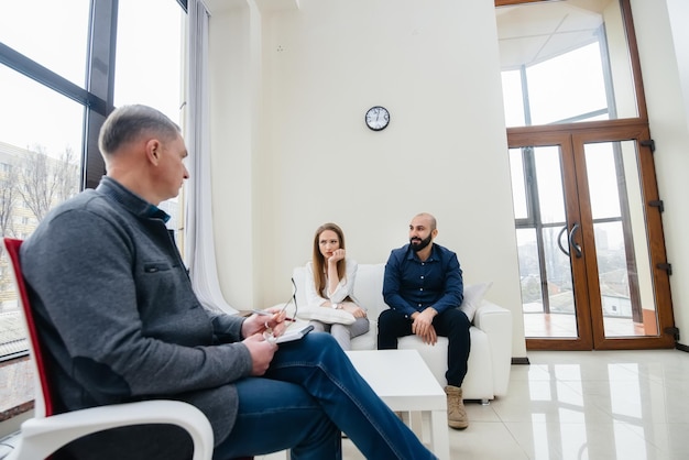 A young married couple of men and women talk to a psychologist at a therapy session. Psychology.