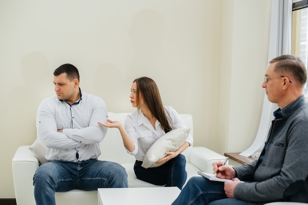 A young married couple of men and women talk to a psychologist at a therapy session. Psychology.