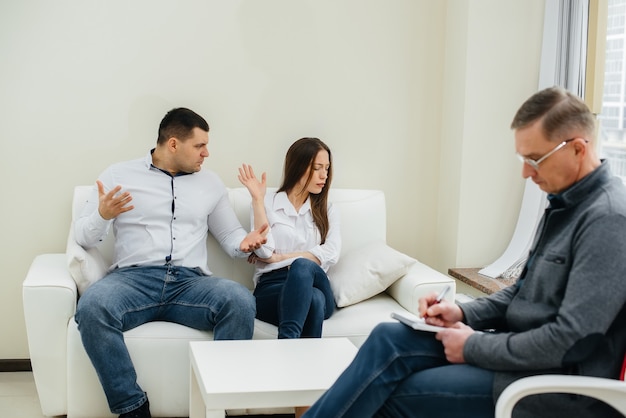 A young married couple of men and women talk to a psychologist at a therapy session. Psychology.