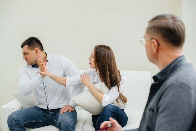 A young married couple of men and women talk to a psychologist at a therapy session. Psychology.