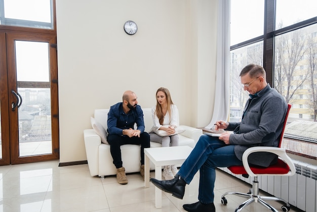 A young married couple of men and women talk to a psychologist\
at a therapy session. psychology.