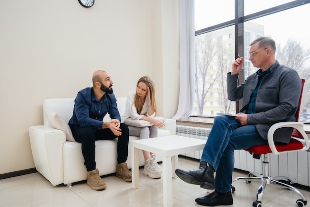 A young married couple of men and women talk to a psychologist\
at a therapy session. psychology.